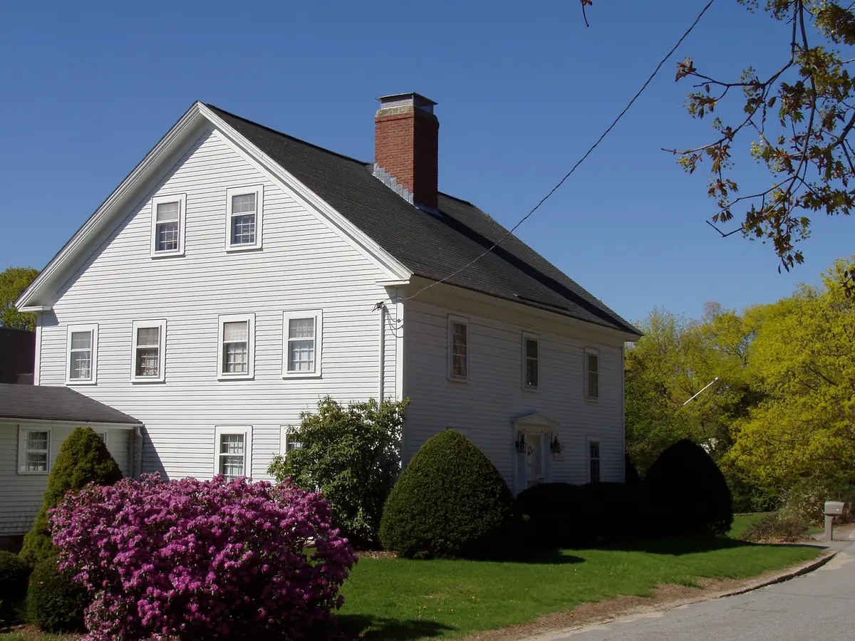 Barrett-Byam Homestead, a white colonial house in Chelmsford, MA, with spring rhododendrons in bloom