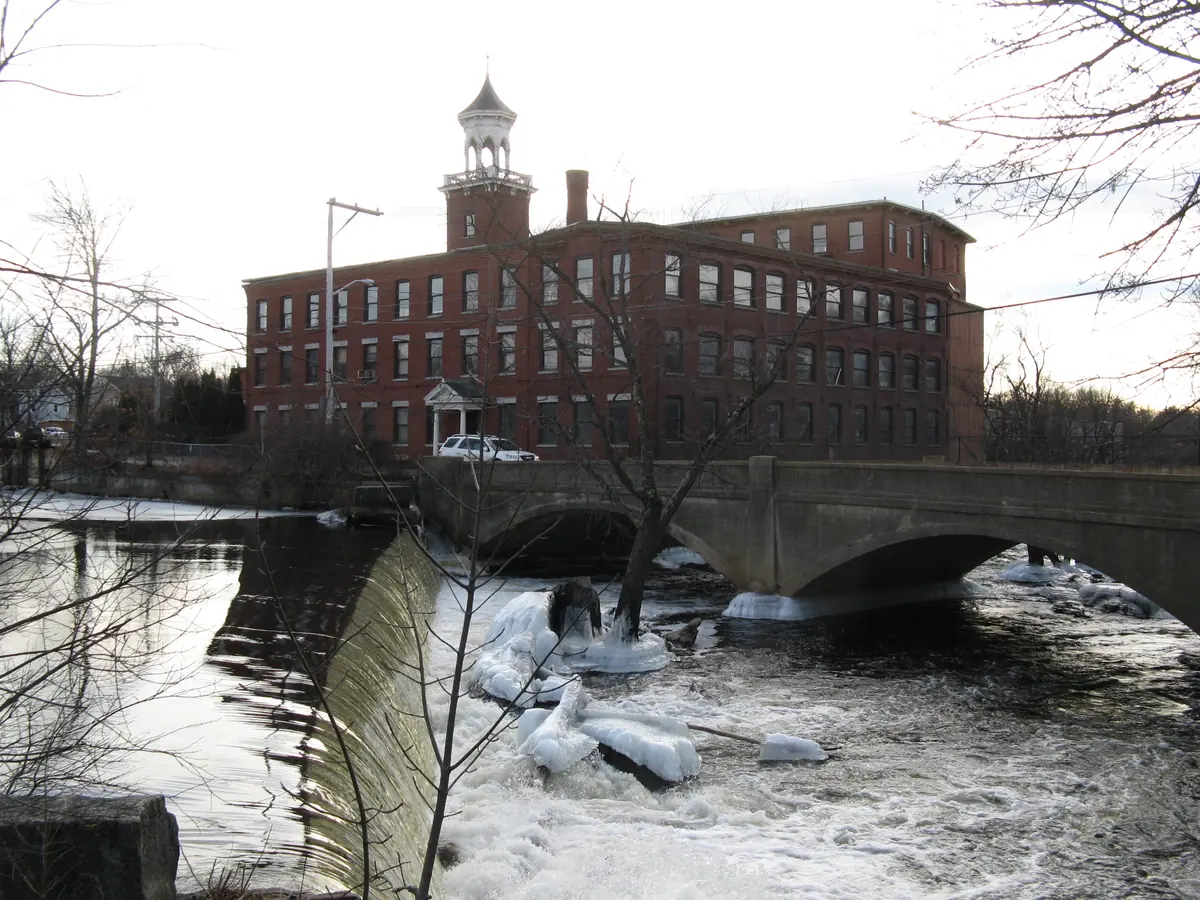 Historic Talbot Mills brick building and bell tower beside the Concord River dam and bridge in North Billerica
