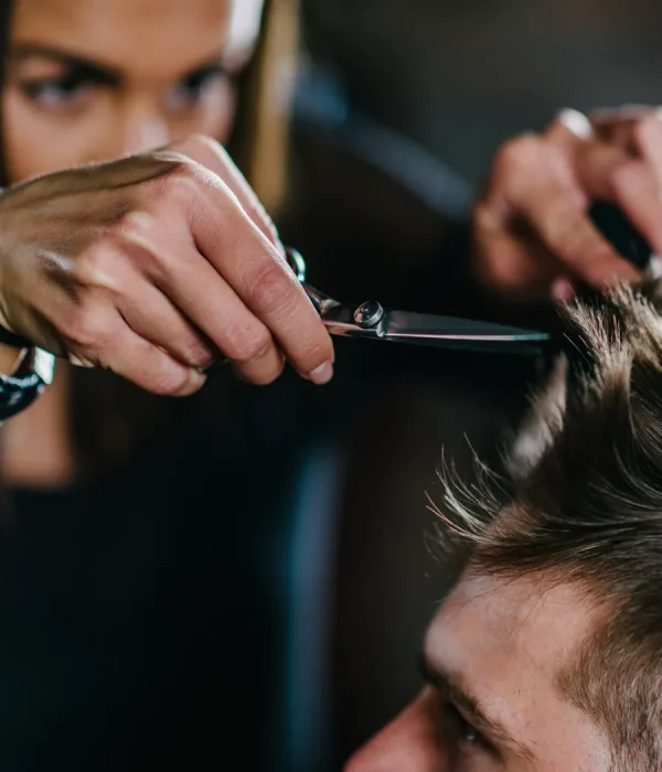 Stylist scissor-cutting the top of a man’s hair during a men’s haircut at Bella Mia Hair Salon in Billerica, MA